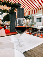 Enjoying a glass of red wine in a cozy, striped tented restaurant during the evening