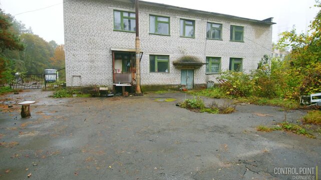Footage of a dilapidated, abandoned building with peeling paint and overgrown vegetation within the Chernobyl Exclusion Zone, close to the infamous Duga radar system.