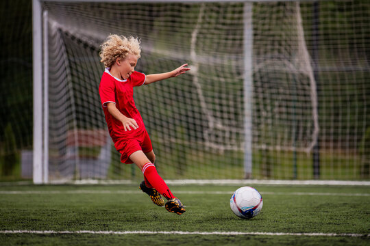young boy performing bicycle kick with football on green field.