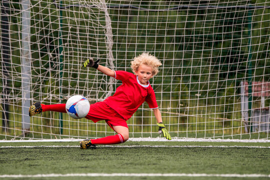 young boy performing bicycle kick with football on green field.