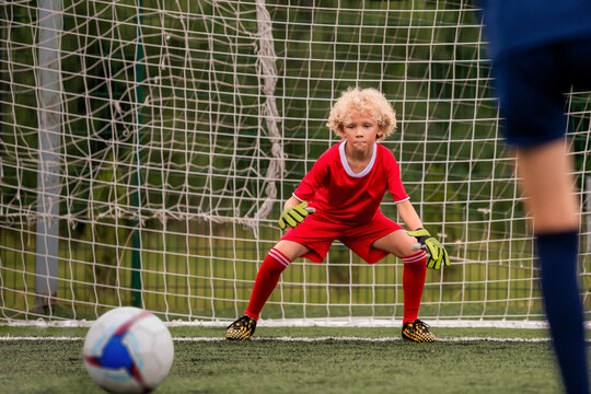 young boy performing bicycle kick with football on green field.