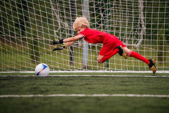 young boy performing bicycle kick with football on green field.