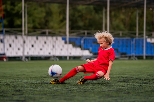 Young boy playing football. Child training on grass field.