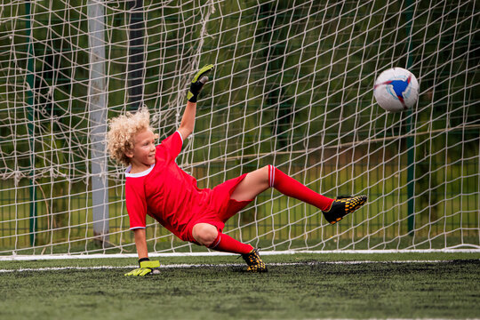 young boy performing bicycle kick with football on green field.
