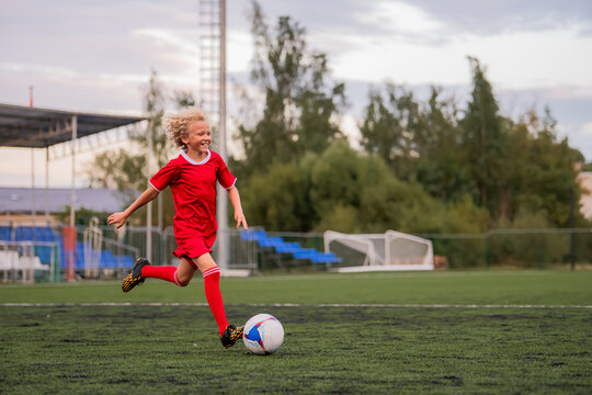 boy with curly hair runs with a football on a green field.