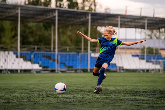 girl soccer player runs on field with ball during training or game.