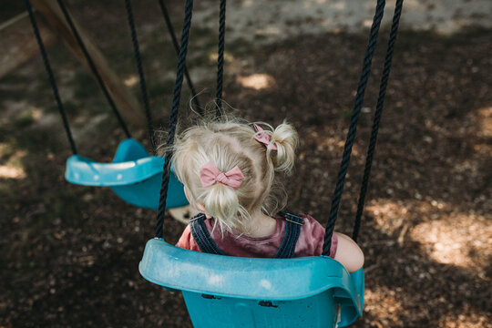 View of young girl in child swing from behind during fall
