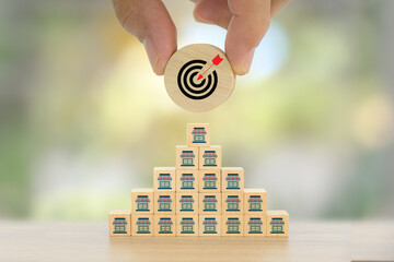 Hand chooses wooden toy block stack with target dart board bullseye and franchise business store for franchising to growth branch expansion and business banking loan or consumer resources service.
