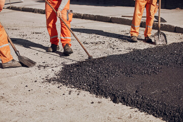 Construction workers working on a new asphalt layer on a public street.