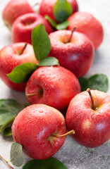 Fresh red apples with water drops and green leaves on gray background