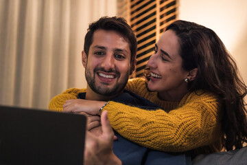 Couple using laptop together at home browsing streaming media and enjoying digital lifestyle connection.