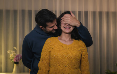 Romantic couple sharing surprise gift at night with love, joy and celebration at home during a special moment together.