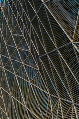 a modern architectural facade, featuring a complex lattice of triangular metal frames. a geometric pattern of shadows and highlights