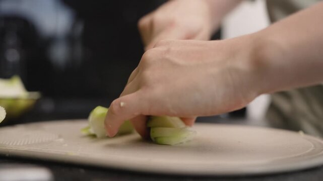Woman chef cutting chayote squash on cutting board