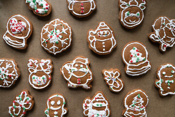 Gingerbread cookies decorated with white icing and sprinkles on brown baking paper, Christmas holiday dessert background, festive winter food for celebration and seasonal design, top view