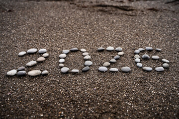 2026 number made of pebbles on sandy beach background, natural texture design for New Year celebration, winter holiday greeting, seasonal decoration, future concept and calendar theme