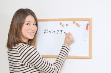 ホワイトボードにメッセージを書き込む若い女性