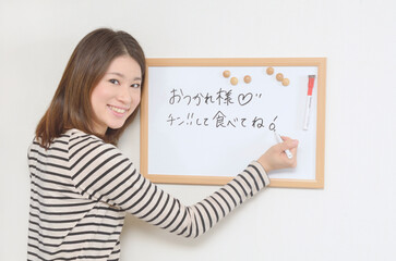 ホワイトボードにメッセージを書き込む若い女性	