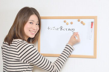 ホワイトボードにメッセージを書き込む若い女性	