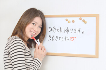 ホワイトボードにメッセージを書き込む若い女性	