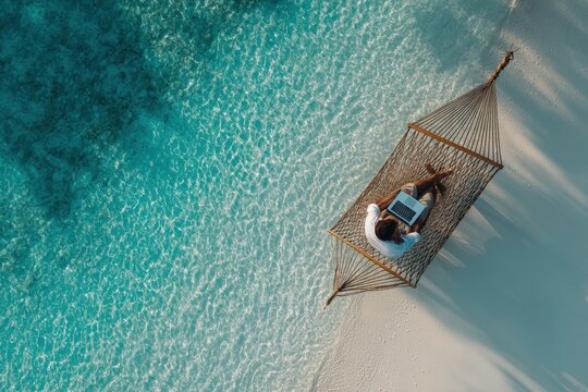 Aerial view of a person working on a laptop in a hammock on a tropical beach (1)