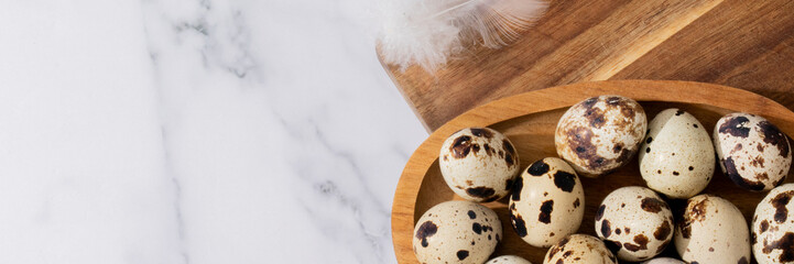 Obraz premium Speckled quail eggs cradle in wooden bowl, embodying rustic spring equinox rituals and gourmet culinary adventures, feather whispers nearby