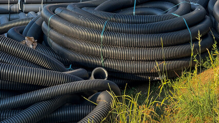 Coiled black hoses snake through sunlit grass, evoking harvest moon rituals and interstellar...