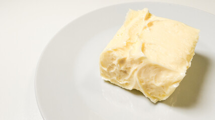 Soft, luscious butter square on porcelain, channeling harvest festival richness and Pancake Day...