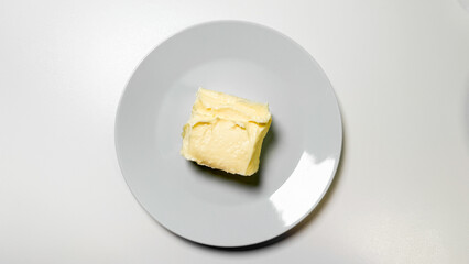A solitary butter square on porcelain whispers farm-to-table elegance, evoking World Butter Day and artisan culinary celebrations