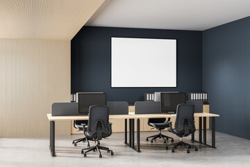Modern open space office interior with shared desks, ergonomic chairs, desktop computers, and a blank poster on a dark blue wall for mockup display. 3D Rendering