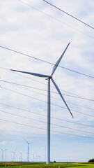 Towering wind turbine in verdant fields symbolizing Eolic Day, renewable energy art, whirring giant...