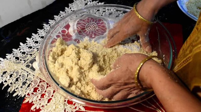 woman hand mixing flour for making dough at kitchen countertop. Indian festive sweet or dessert preparation, thekua puri laddu items