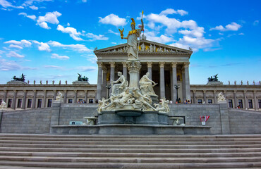 A majestic view of the historic Austrian Parliament Building and the magnificent Pallas Athene Fountain under a vibrant blue sky in Vienna