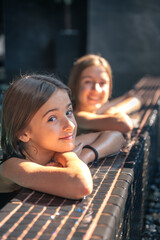 Smiling girl at the pool edge with soft highlights and warmth. Friendly vibe.