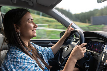 Naklejka premium Smiling woman driving a car. Road trip behind the wheel