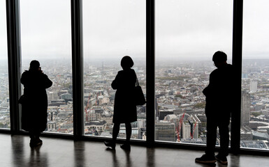 Silhouetted and anonymous tourists enjoying panoramic view of London from high rise observatory