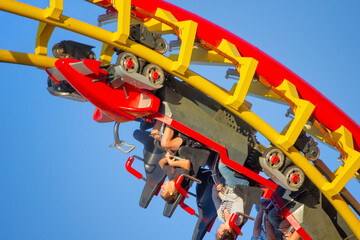 Riders experience an exhilarating upside-down inversion on a vibrant red and yellow roller coaster