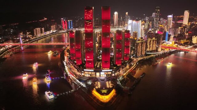 Drone aerial video of Chongqing at night showing illuminated skyscrapers, glowing skyline, colorful reflections on the river, above vibrant boats and traffic moving in cinematic view slow motion