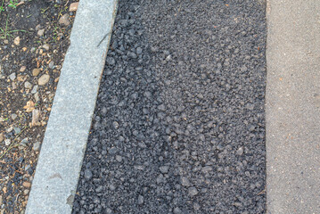 Fototapeta premium Repair of road pits. Sealing holes in the road with asphalt. A curb has been laid along the sidewalk. Road surface replacement work. Repair of a sidewalk on a street in the city.