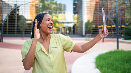 Excited businesswoman video calling with tablet in a business park