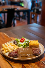 Medium rare meat steak, topped with black pepper sauce on plate with French fries and bread.Medium rare meat steak, topped with black pepper sauce on plate with French fries and bread.