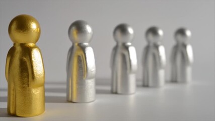 A golden figurine stands apart from a line of identical silver figurines against a neutral background.