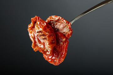 Sun dried tomatoes in olive oil on a fork.