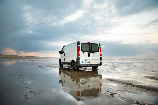 Camper van driving next to wadden sea at low tide, traveling at beach of Romo, Denmark, adventure vacation und lifestyle, winter