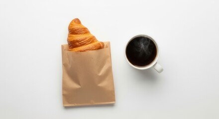 A top-down view of a croissant in a paper bag next to a steaming mug of black coffee on a white surface