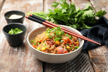 Delicious fried rice in bowl served on wooden table, closeup