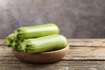 Fresh ripe zucchinis on wooden table, closeup. Space for text