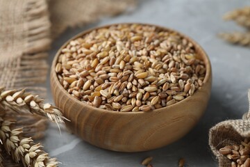 Wheat grain and spikes on light grey table, closeup