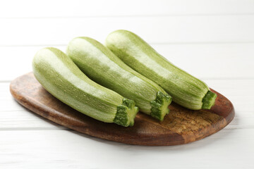 Fresh ripe zucchinis on white wooden table, closeup