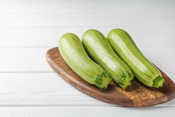 Fresh ripe zucchinis on white wooden table, closeup. Space for text
